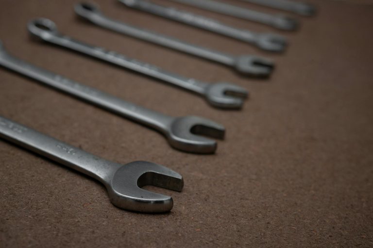 A detailed photo of silver metallic spanners laid on a brown surface.