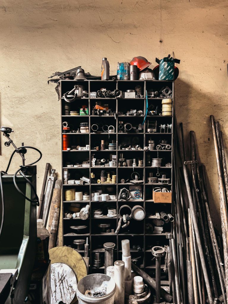 A well-organized workshop shelf with various industrial tools and pipes in a garage setting.
