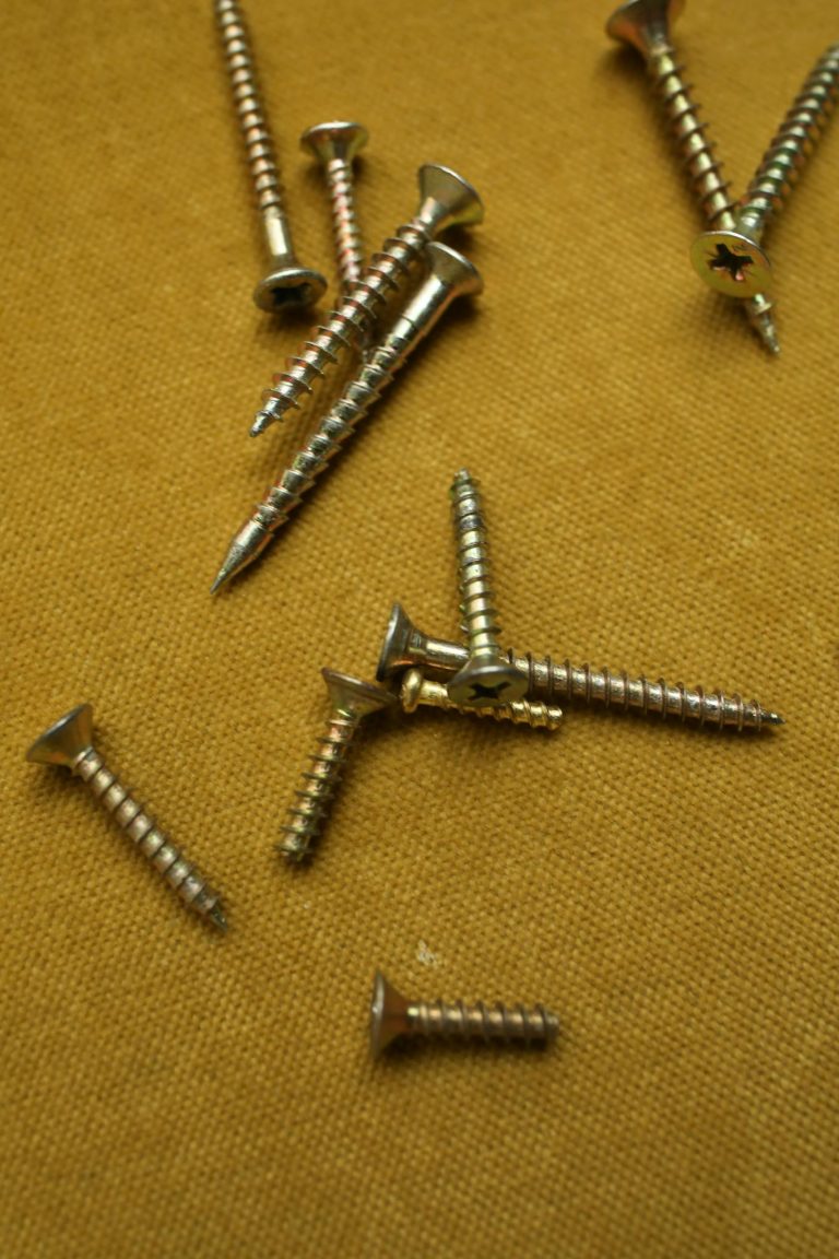 An assortment of metallic screws on a textured brown surface.